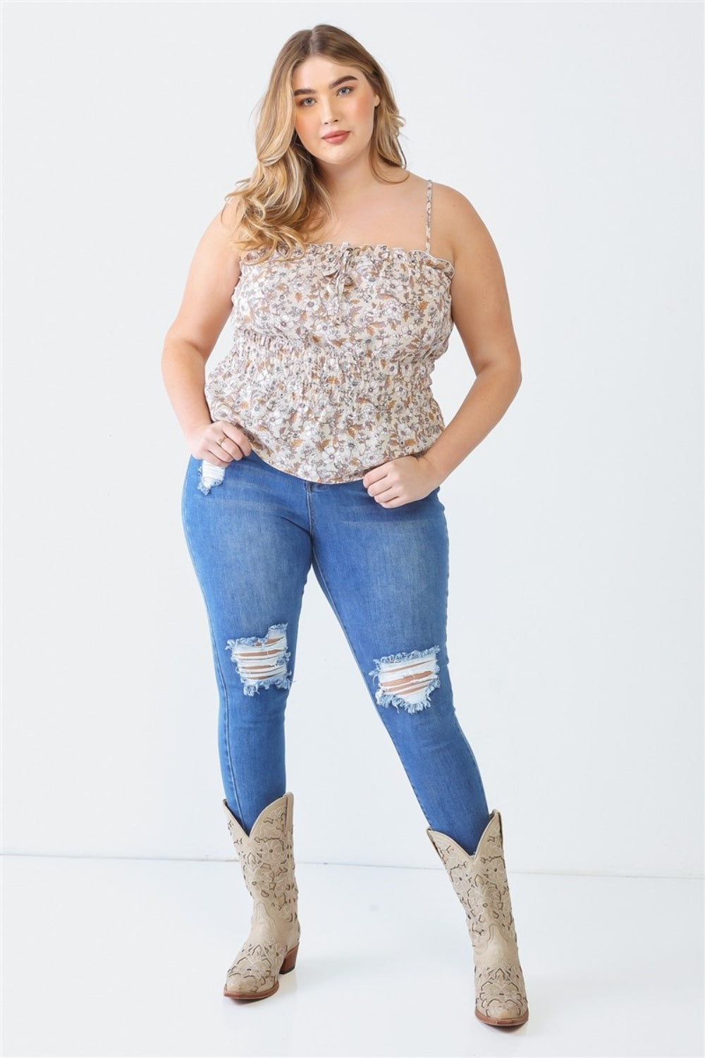 A person with long hair, wearing the Zenobia Plus Size Frill Floral Square Neck Cami and dark jeans, stands with one hand on their hip and the other relaxed by their side.