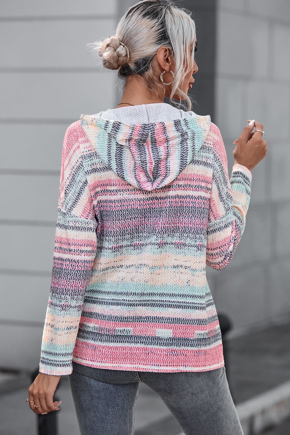 A person with light hair tied up is wearing the Multicolor Striped Print Cable Knit Drop Shoulder Hoodie while standing outdoors, facing away from the camera.