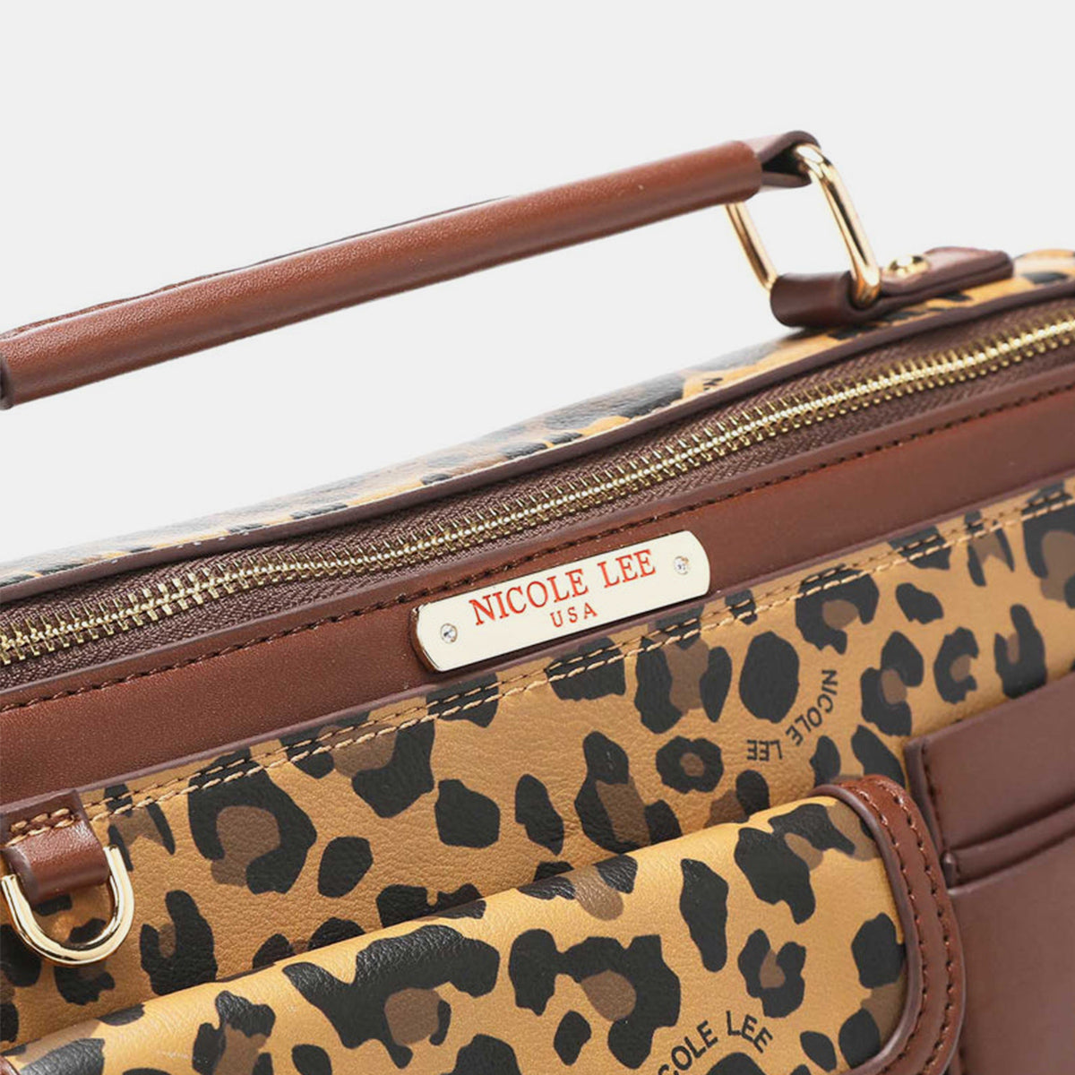 The Nicole Lee USA Leopard Top Handle Handbag is a stylish accessory with chic leopard print and brown vegan leather accents. It boasts two outer pockets, a gold-tone zip closure, and includes a versatile crossbody strap for convenient carrying.