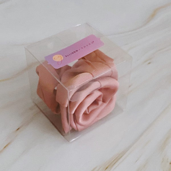 Four high-quality Art Of Work Satin Rose Scrunchies in black, pink, green, and cream arranged on a marble surface.