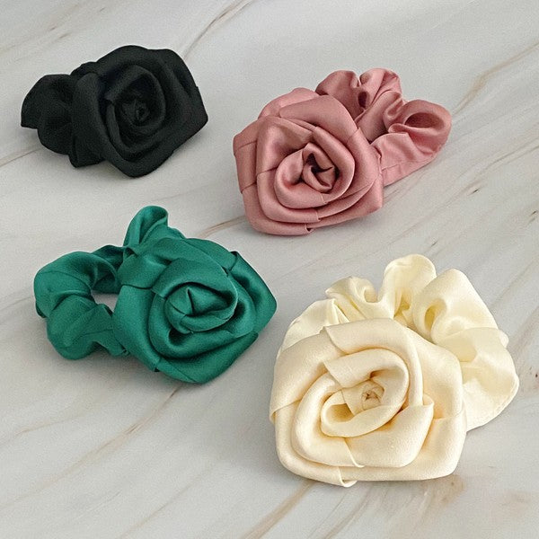 Four high-quality Art Of Work Satin Rose Scrunchies in black, pink, green, and cream arranged on a marble surface.