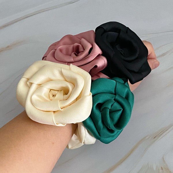 Four high-quality Art Of Work Satin Rose Scrunchies in black, pink, green, and cream arranged on a marble surface.