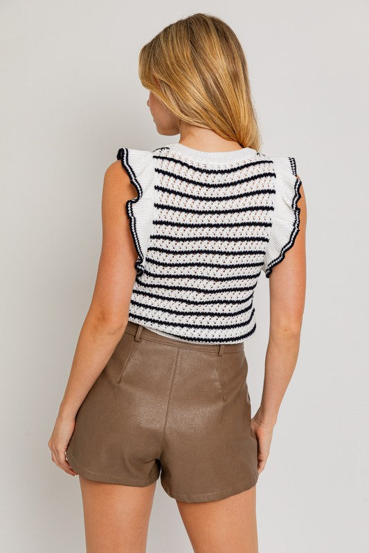 A woman is wearing a Round Neck Ruffle Sleeve Stripe Knit Top in a chic print, sleeveless white and brown stripe design, paired with light blue denim shorts, standing against a plain background.