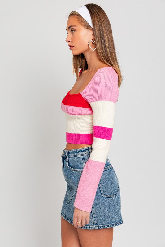 A person stands facing the camera, wearing a Long Sleeve Color Block Stripe Knit Top and a blue denim skirt. They have long hair with a white headband.