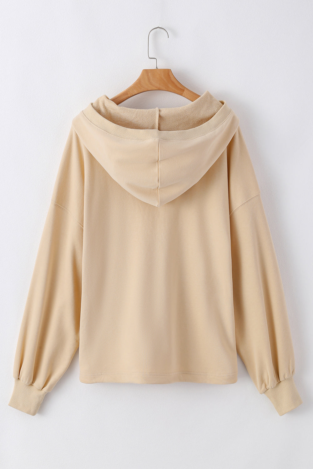 A person with long brown hair is standing with their back to the camera, wearing a Parchment Solid Kangaroo Pocket Half Zipper Oversized Hoodie and black shorts.