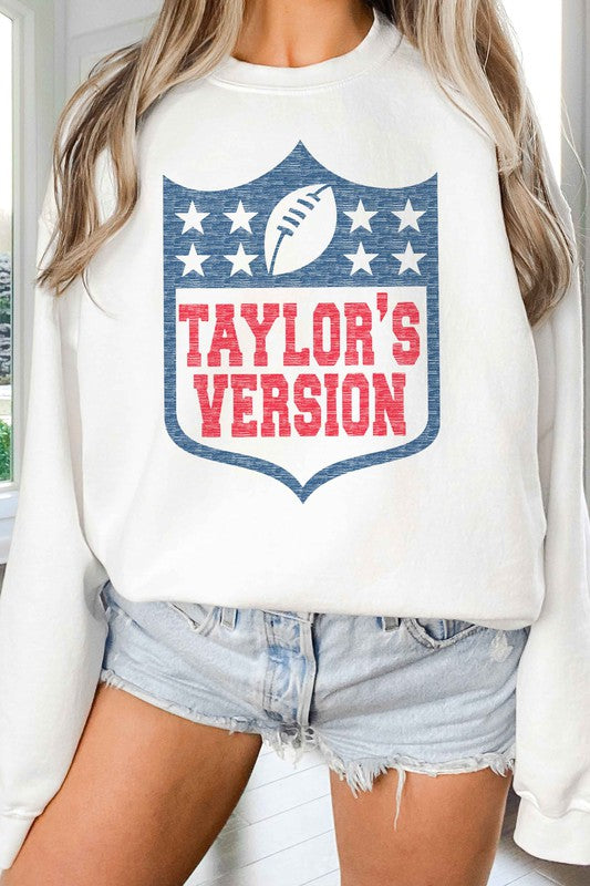 A person wearing the TAYLORS VERSION FOOTBALL GRAPHIC SWEATSHIRT, made of premium cream-colored cotton and featuring "TAYLOR'S VERSION" along with a football graphic on the front.