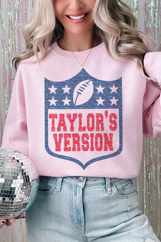 A person wearing the TAYLORS VERSION FOOTBALL GRAPHIC SWEATSHIRT, made of premium cream-colored cotton and featuring "TAYLOR'S VERSION" along with a football graphic on the front.