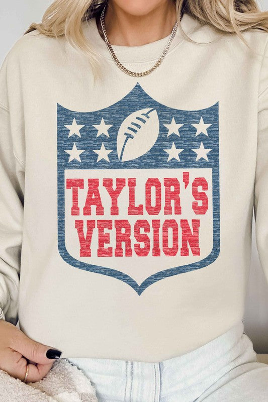 A person wearing the TAYLORS VERSION FOOTBALL GRAPHIC SWEATSHIRT, made of premium cream-colored cotton and featuring "TAYLOR'S VERSION" along with a football graphic on the front.