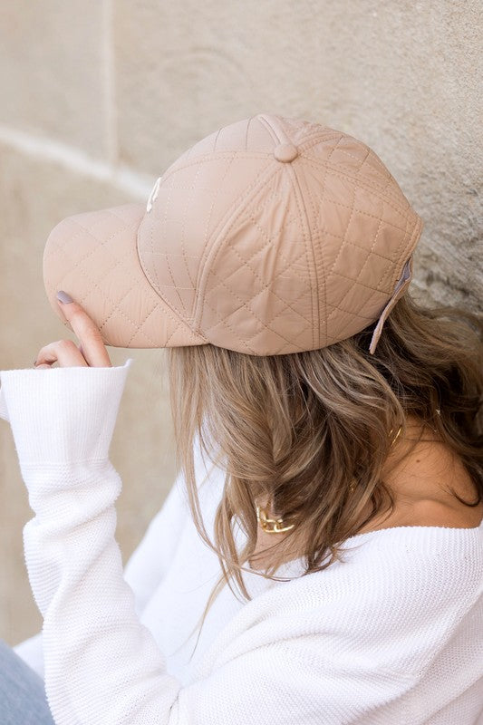 Woman smiling and tipping an adjustable-fit Quilted Puffer Ball Cap.