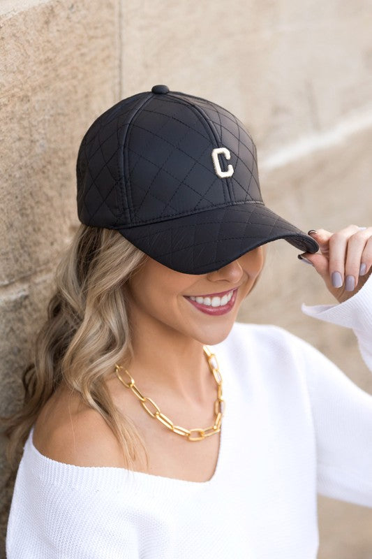 Woman smiling and tipping an adjustable-fit Quilted Puffer Ball Cap.