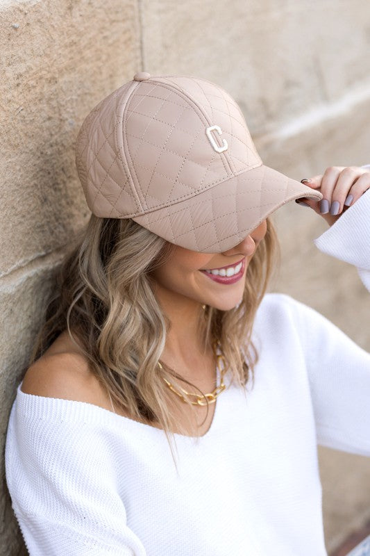 Woman smiling and tipping an adjustable-fit Quilted Puffer Ball Cap.