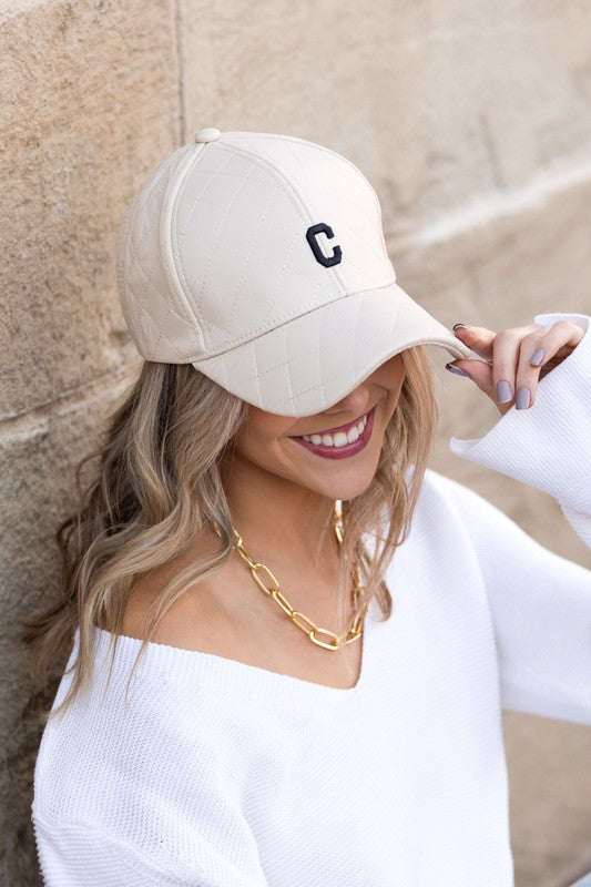 Woman smiling and tipping an adjustable-fit Quilted Puffer Ball Cap.