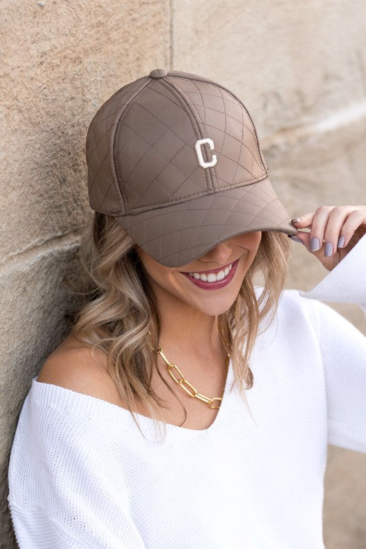 Woman smiling and tipping an adjustable-fit Quilted Puffer Ball Cap.