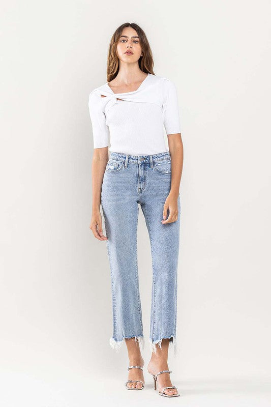 A person wearing light blue High Rise Distressed Hem Crop Dad Jeans, a white short-sleeve top, and silver open-toe heels stands against a plain background.