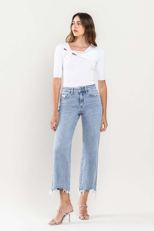 A person wearing light blue High Rise Distressed Hem Crop Dad Jeans, a white short-sleeve top, and silver open-toe heels stands against a plain background.