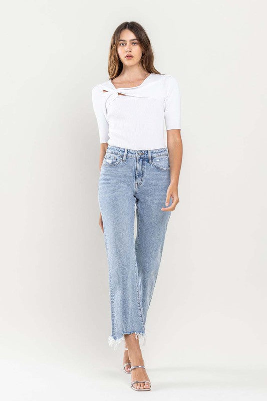 A person wearing light blue High Rise Distressed Hem Crop Dad Jeans, a white short-sleeve top, and silver open-toe heels stands against a plain background.