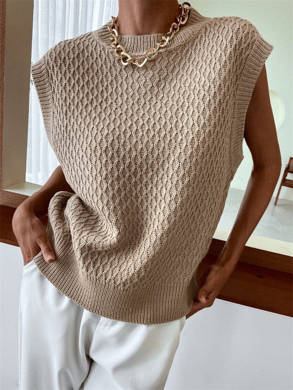 Person wearing the Knit Sweater Vest in beige and a chunky gold necklace, paired with white pants.