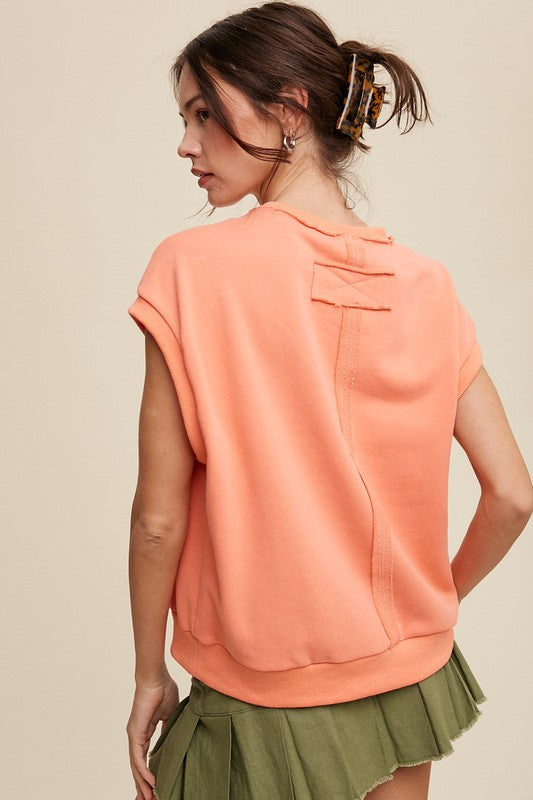 A woman stands against a neutral background, wearing the Short Sleeve Boxy Crew Neck Sweat Top in blue with ribbed detailing over a white button-up shirt.