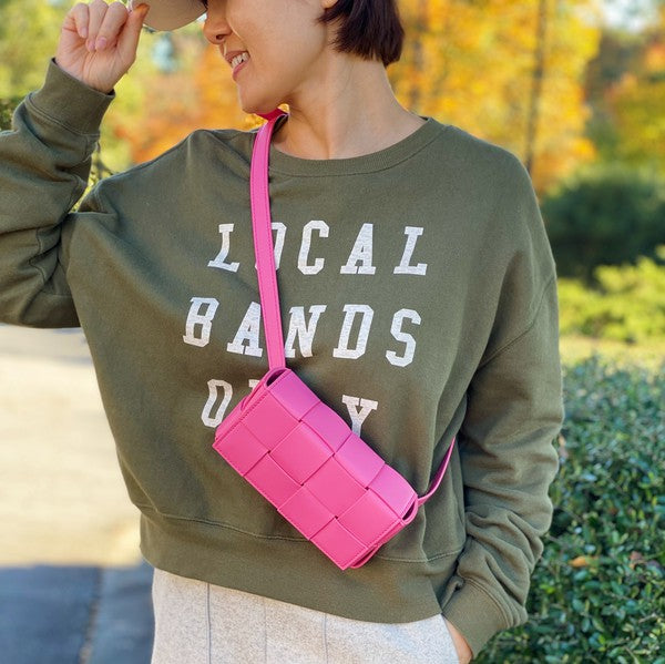 Three small Candy Cube Woven Sling Bags in green, pink, and black, made from faux leather PU material, being held by a hand against a white background.