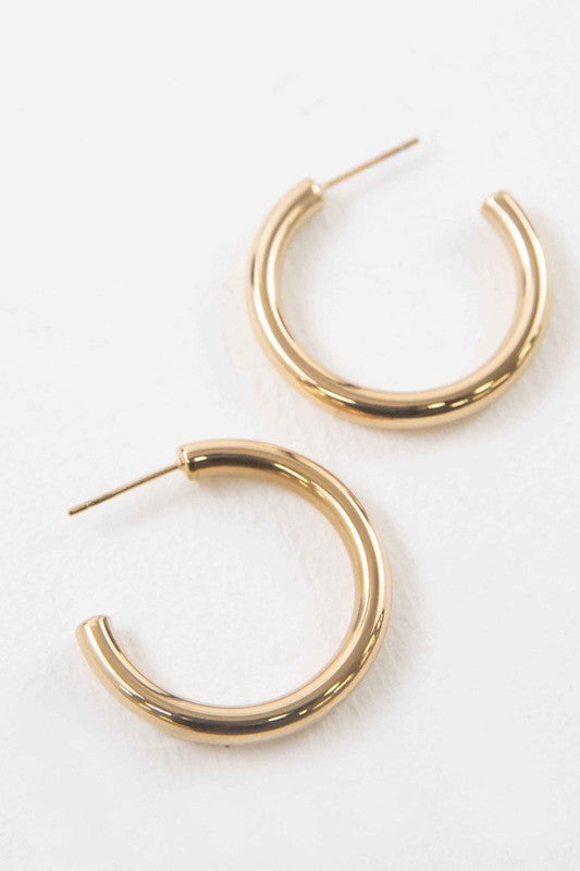 The Canal Hoop Earrings, with their lustrous 14k gold plating, are artfully displayed on a white background, highlighting their hypoallergenic allure.