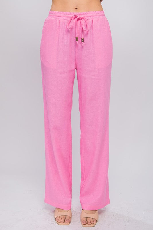 Person wearing vibrant pink Linen Drawstring Waist Long Pants with Pockets featuring a relaxed fit and a brownish sweater, standing with hands in pockets against a neutral background.