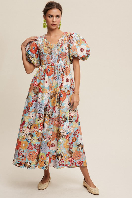 A woman in a Flower Print Smocked V-neck Puff Sleeve Maxi Dress stands gracefully against a plain background.