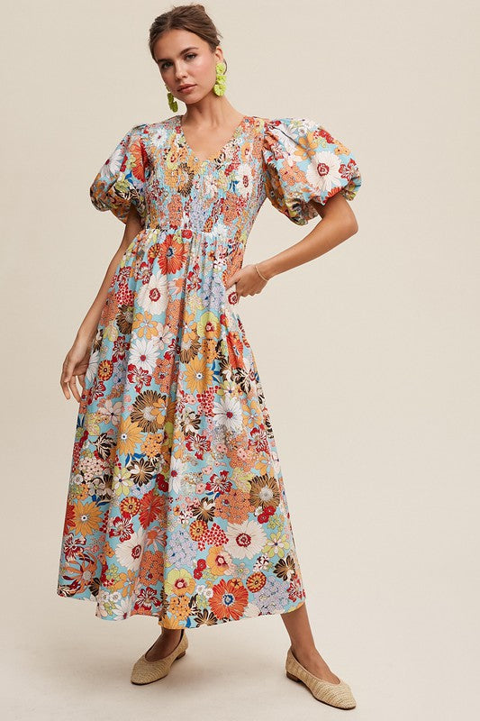 A woman in a Flower Print Smocked V-neck Puff Sleeve Maxi Dress stands gracefully against a plain background.