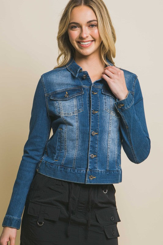 A woman wearing a Distressed Button Up Stretchy Cotton Denim Jacket and black pants, smiling at the camera.