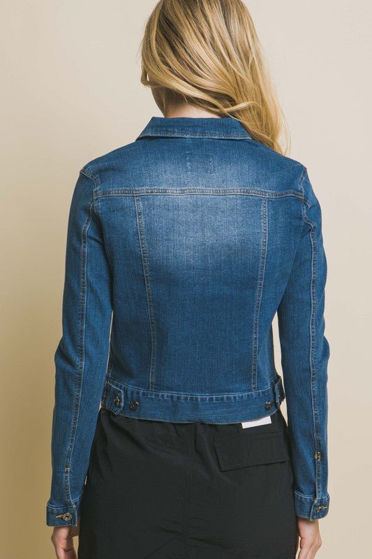 A woman wearing a Distressed Button Up Stretchy Cotton Denim Jacket and black pants, smiling at the camera.