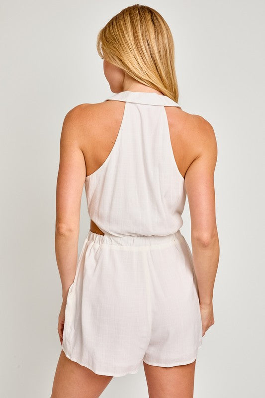 A person wearing the Collared Sleeveless Romper smiles with eyes closed and one hand on their hip, exuding effortless charm with its tailored fit and lightweight fabric.