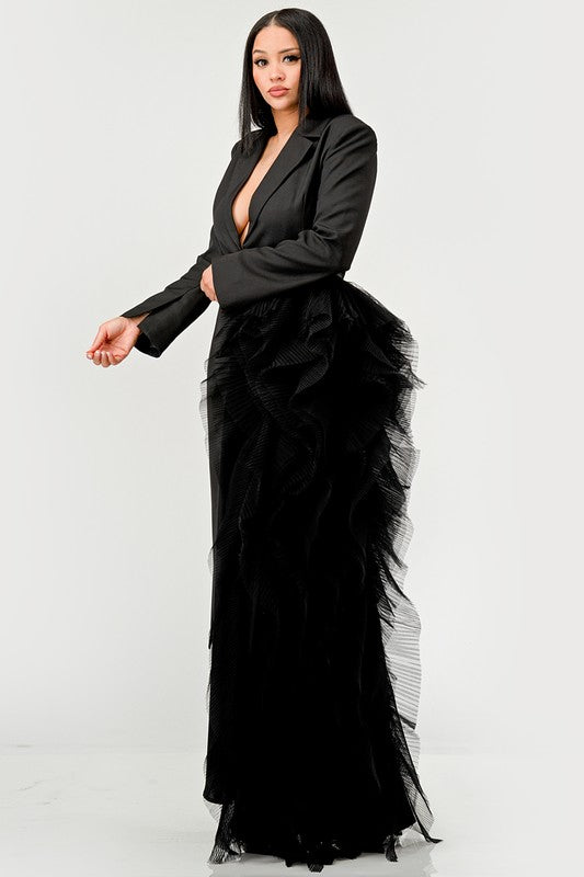 Person wearing the Noir Cascade Tuxedo Gown, which features structured shoulders, a deep V neckline, and a cascading ruffle skirt, paired with clear high-heeled shoes, exuding couture elegance.