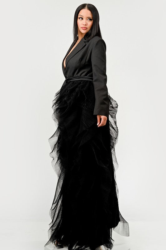 Person wearing the Noir Cascade Tuxedo Gown, which features structured shoulders, a deep V neckline, and a cascading ruffle skirt, paired with clear high-heeled shoes, exuding couture elegance.