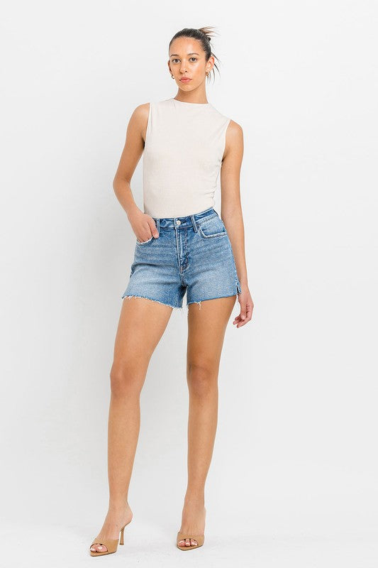 A person wearing high-rise side slit A-line shorts and a sleeveless top stands confidently against a white background.