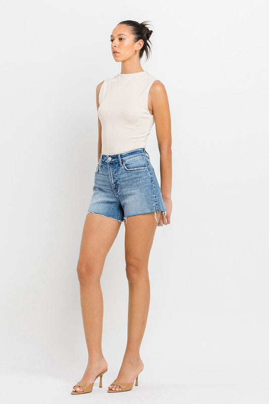 A person wearing high-rise side slit A-line shorts and a sleeveless top stands confidently against a white background.