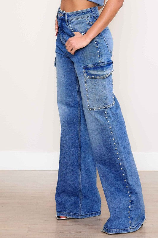 A person stands against a plain backdrop, dressed in a denim crop top and the Pearl High-Rise Wide Leg Cargo Jeans. Their hands rest casually by their sides, highlighting the effortless style of this denim collection.