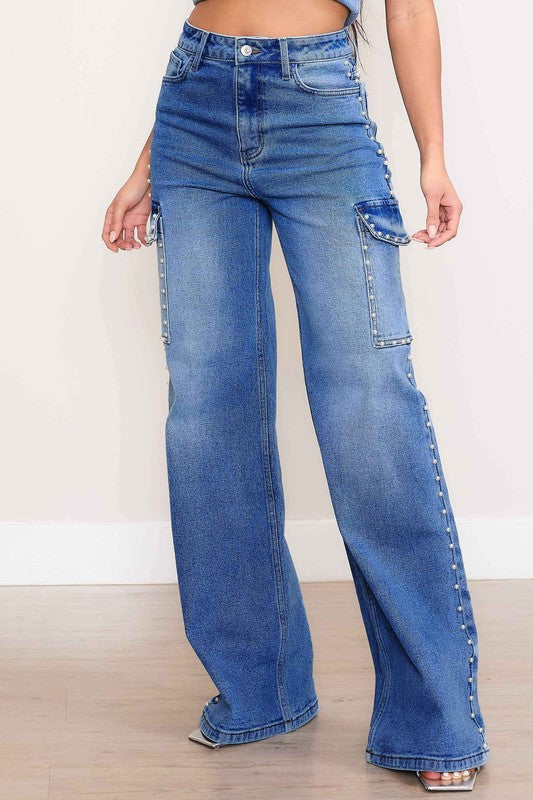 A person stands against a plain backdrop, dressed in a denim crop top and the Pearl High-Rise Wide Leg Cargo Jeans. Their hands rest casually by their sides, highlighting the effortless style of this denim collection.