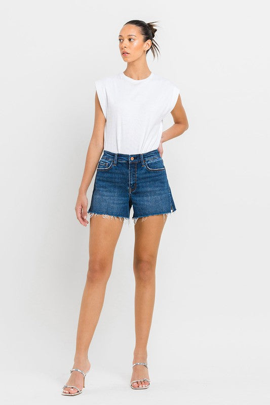 A person wearing High Rise Slit Raw Hem A-Line Shorts and silver sandals stands against a white background.