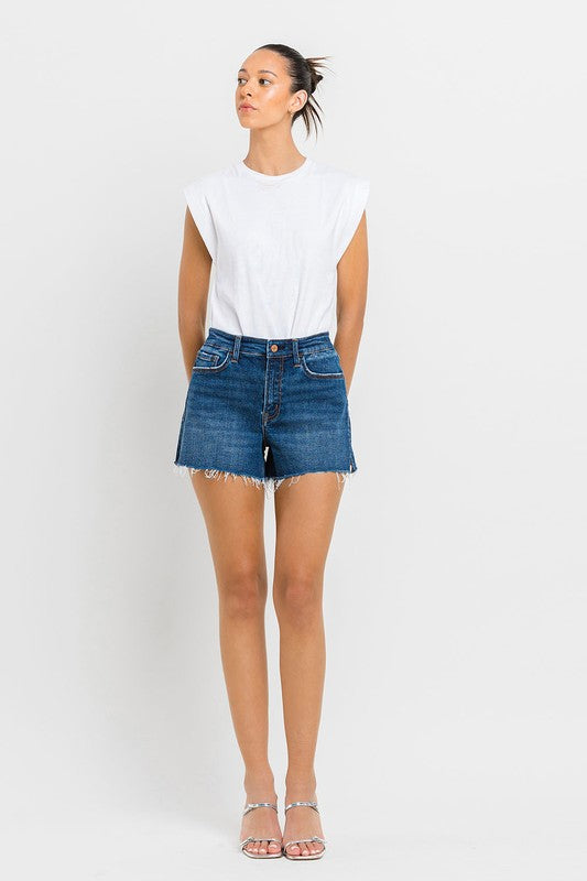 A person wearing High Rise Slit Raw Hem A-Line Shorts and silver sandals stands against a white background.