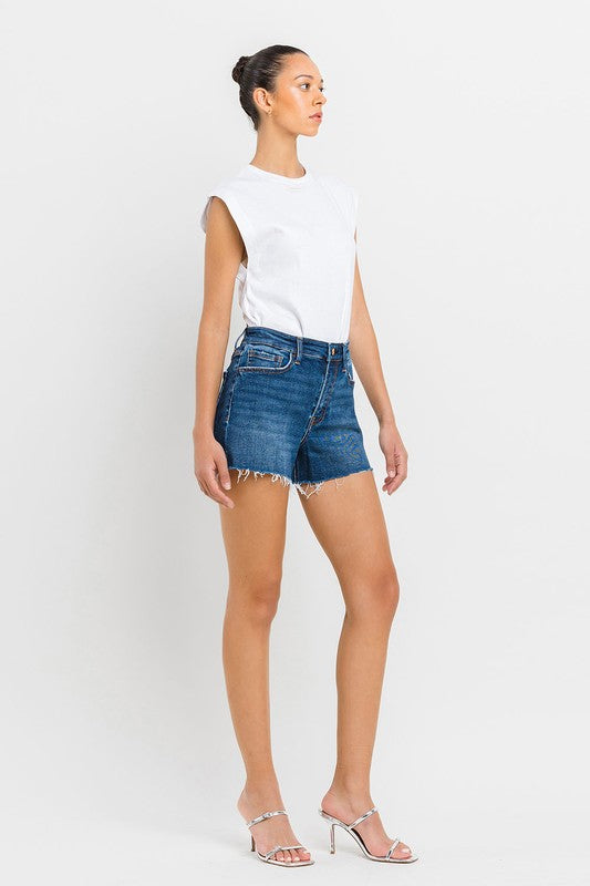 A person wearing High Rise Slit Raw Hem A-Line Shorts and silver sandals stands against a white background.