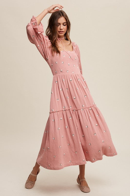 A woman is gracefully wearing the Ditzy Floral Embroidery Puff Sleeve Maxi Dress, complemented by beige shoes, as she stands against a plain background.