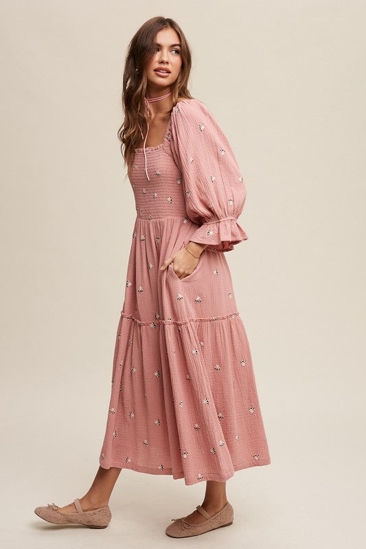 A woman is gracefully wearing the Ditzy Floral Embroidery Puff Sleeve Maxi Dress, complemented by beige shoes, as she stands against a plain background.