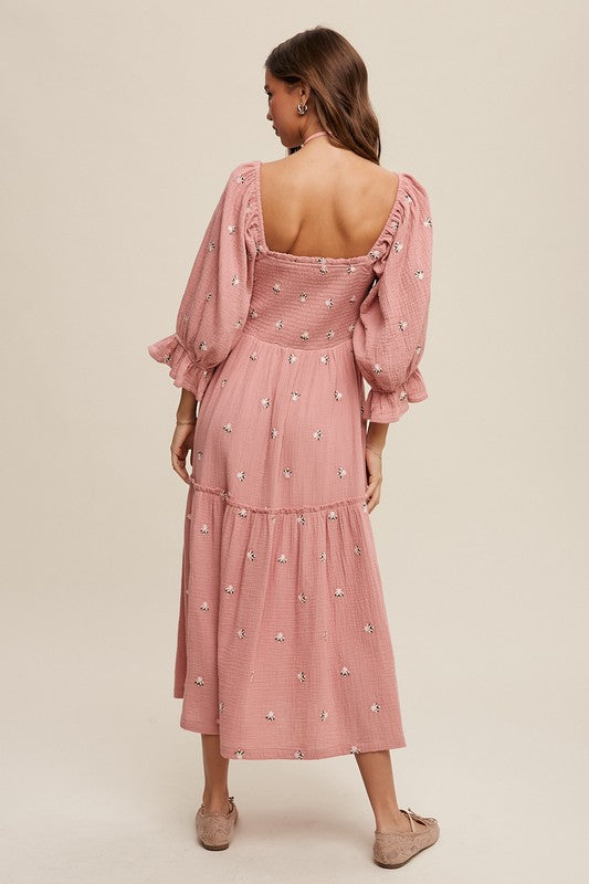 A woman is gracefully wearing the Ditzy Floral Embroidery Puff Sleeve Maxi Dress, complemented by beige shoes, as she stands against a plain background.