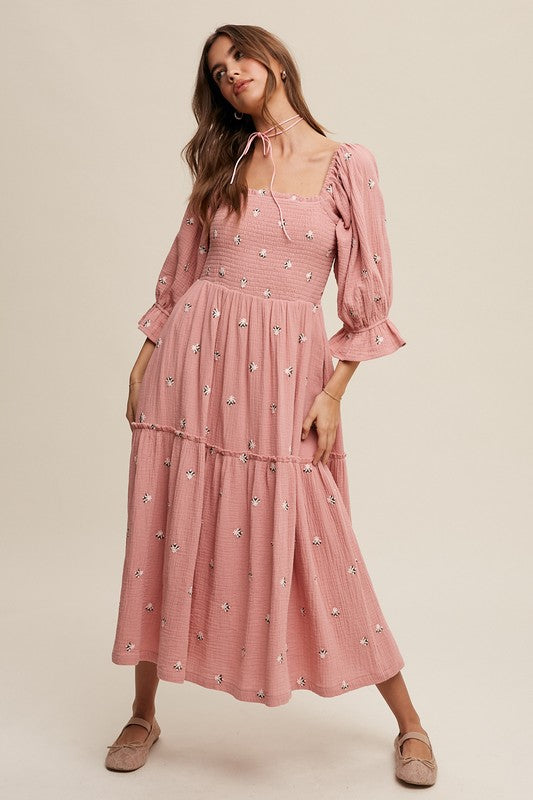 A woman is gracefully wearing the Ditzy Floral Embroidery Puff Sleeve Maxi Dress, complemented by beige shoes, as she stands against a plain background.