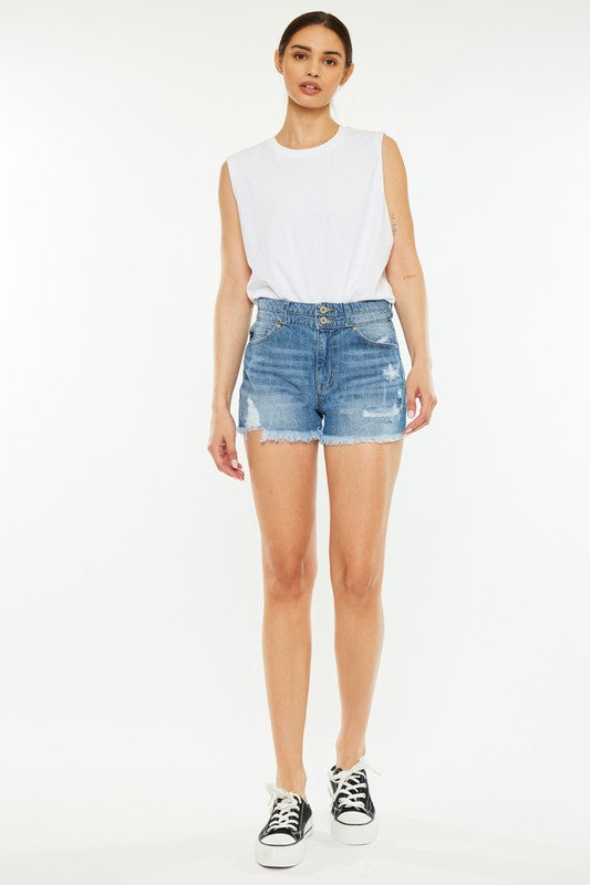 A person wearing a white sleeveless shirt, High Rise Mom Shorts in stone wash denim, and black-and-white sneakers stands against a plain background.