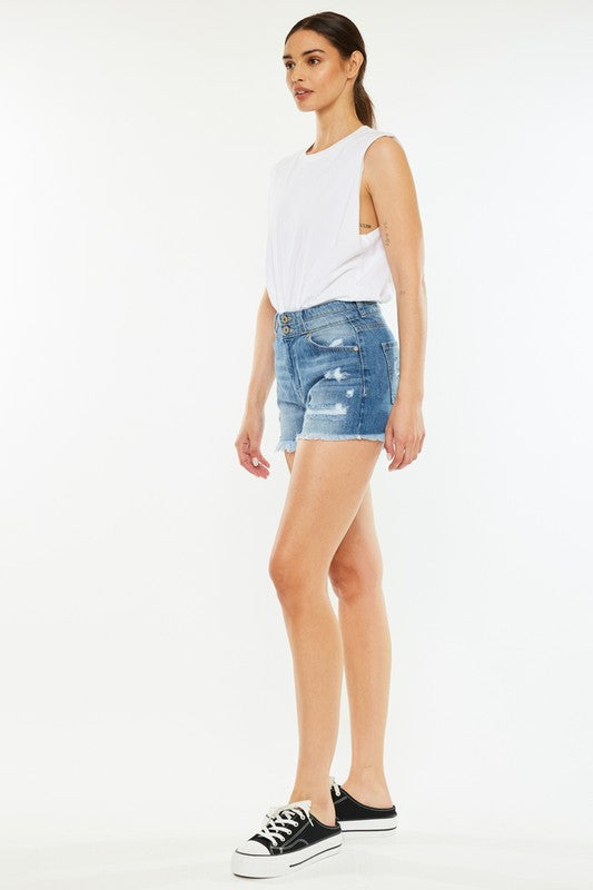 A person wearing a white sleeveless shirt, High Rise Mom Shorts in stone wash denim, and black-and-white sneakers stands against a plain background.