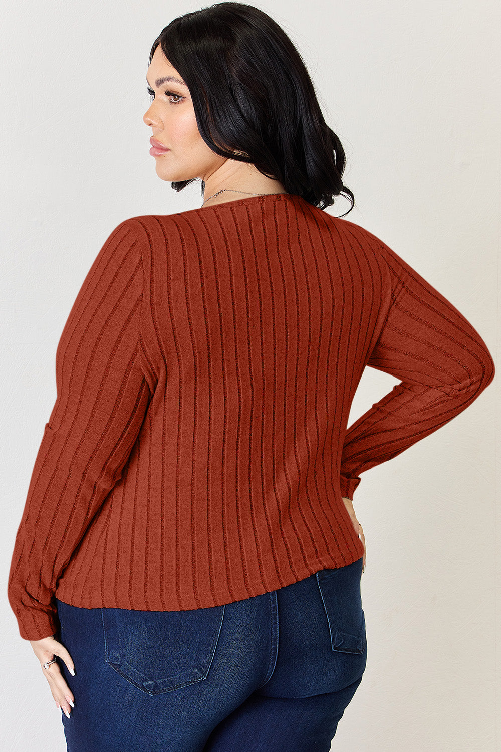 A person is standing and smiling, wearing the Basic Bae Full Size Ribbed Long Sleeve T-Shirt in light brown along with jeans. The basic style is perfect for any casual outing.