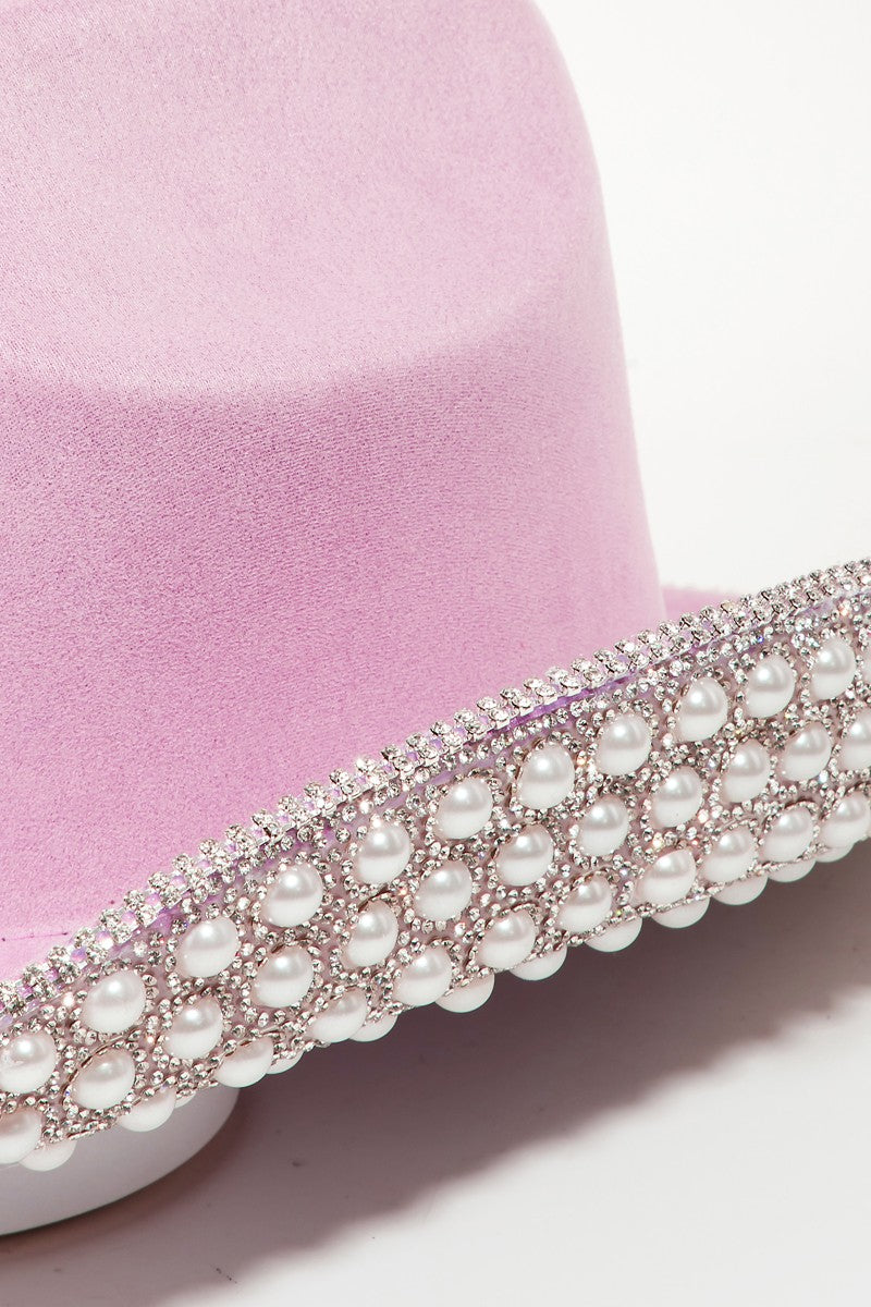 Introducing the Fame Pave Rhinestone Pearl Trim Cowboy Hat: a glamorous Western accessory in light pink, featuring exquisite silver beading along the brim, set against a plain white backdrop.