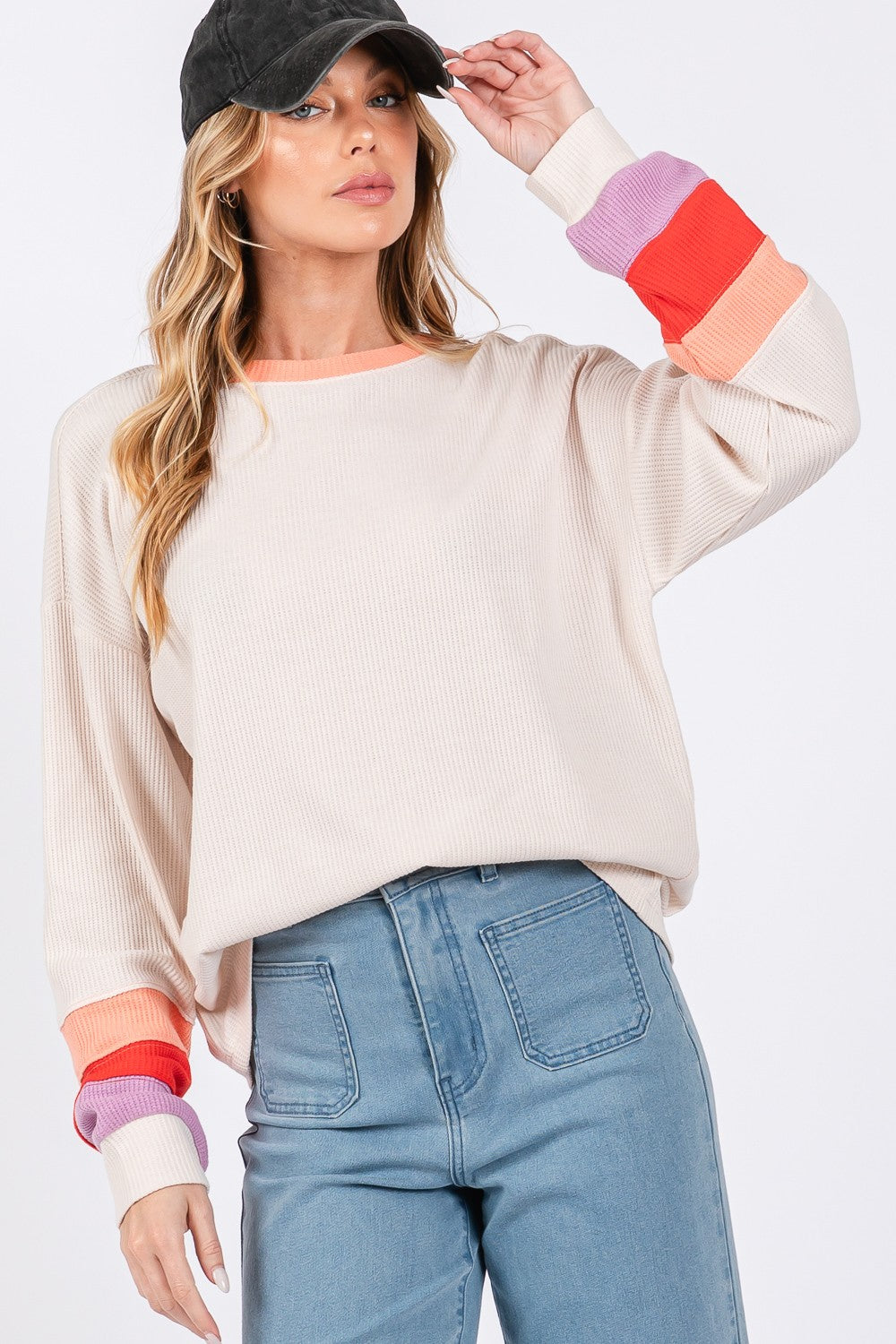 A person wearing the SAGE + FIG Color Block Waffle Knit T-Shirt, blue jeans, and a black cap stands against a plain background.