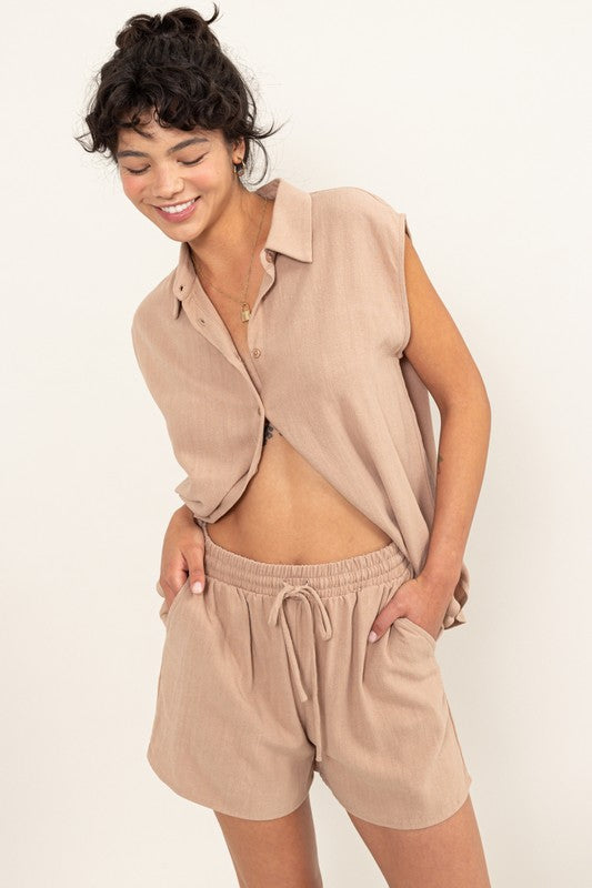 Against a beige backdrop, a woman effortlessly embodies summer style in the Linen Shirt and Shorts Set, featuring a relaxed fit that exudes chic simplicity.