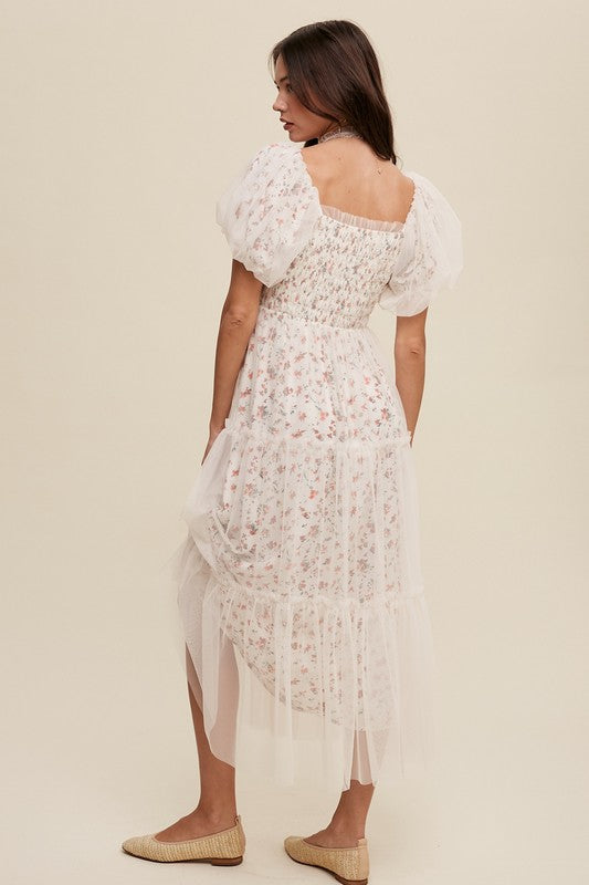 A woman in a Floral Print and Mesh Puff Sleeve Maxi Dress stands against a plain background, looking slightly to the side.